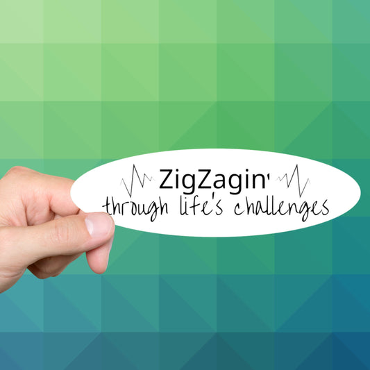 Hand holding a ZigZagin' through life's challenges oval sewing sticker on a green background