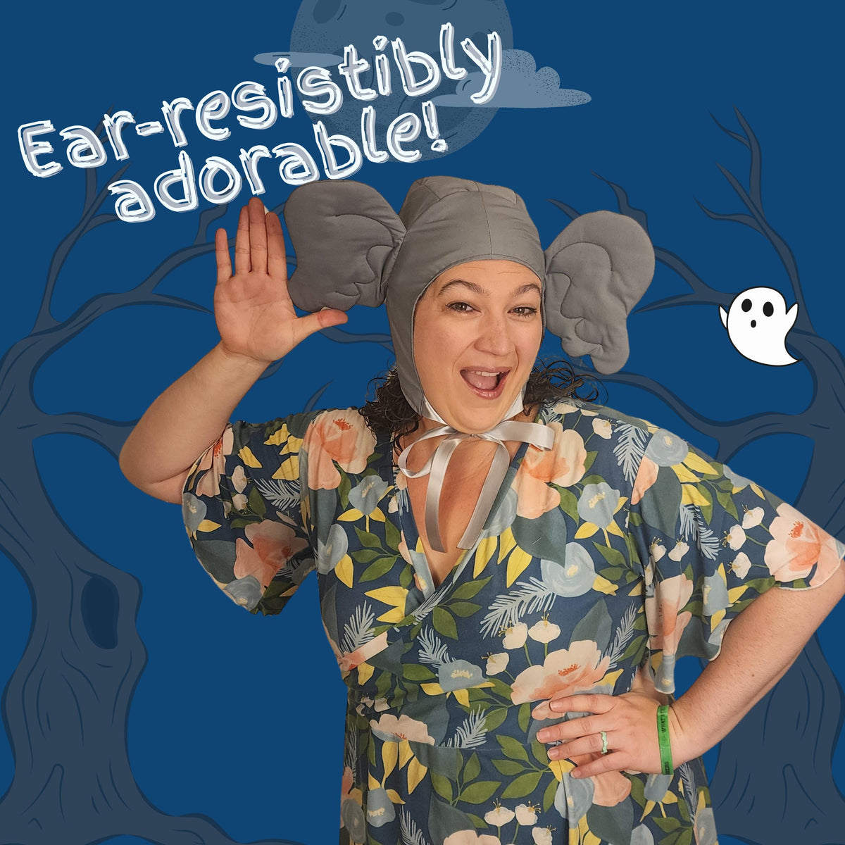 Woman waving in a gray elephant ear hood on a spooky blue background: ear-resistibly adorable