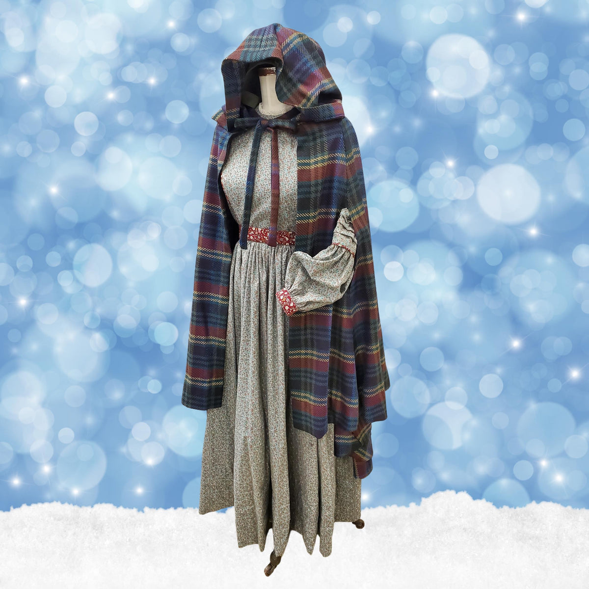 Plaid hooded caroling cape on a dress form on a snowy winter background