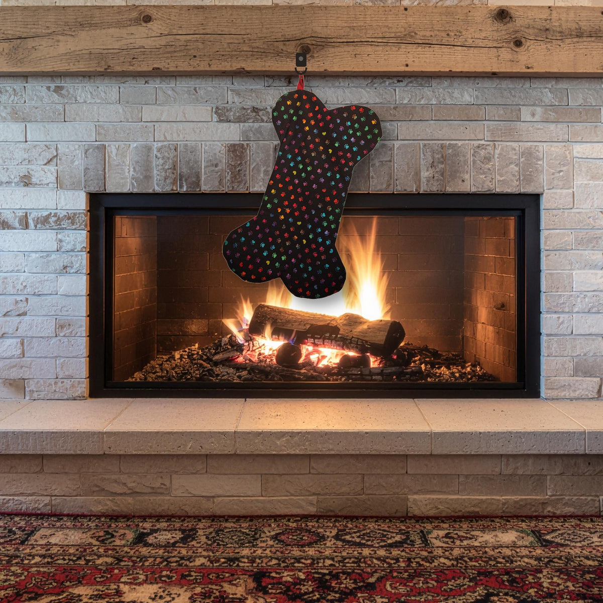 Black dog bone stocking with rainbow paw prints hanging on a fireplace mantel