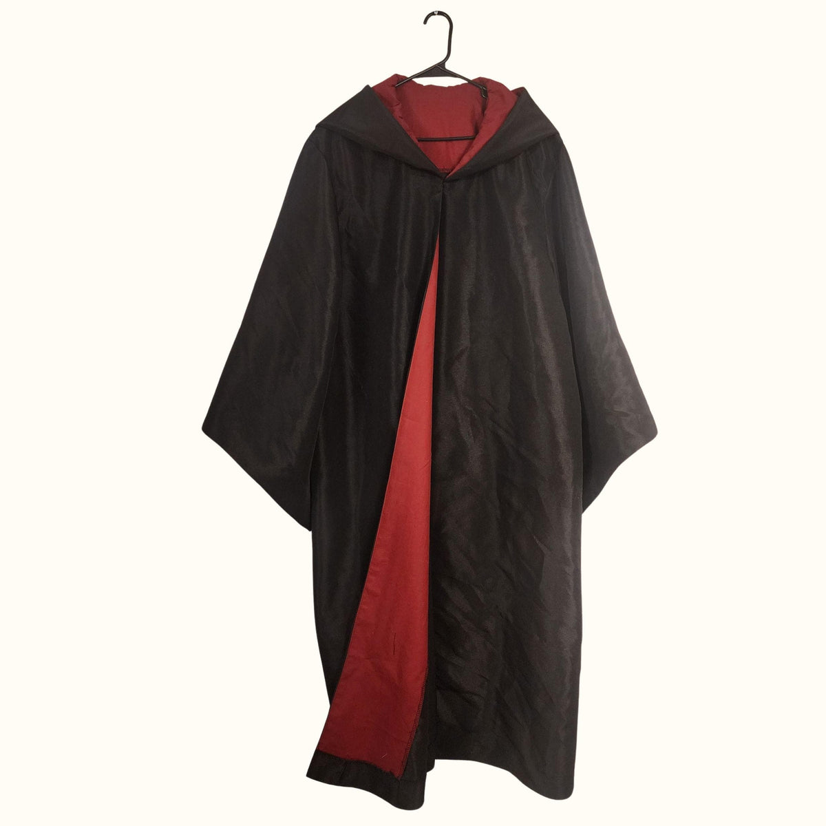 Finished black wizard robe on a hanger with a pointed hood and red contrast facing down the front and inside the long bell sleeves