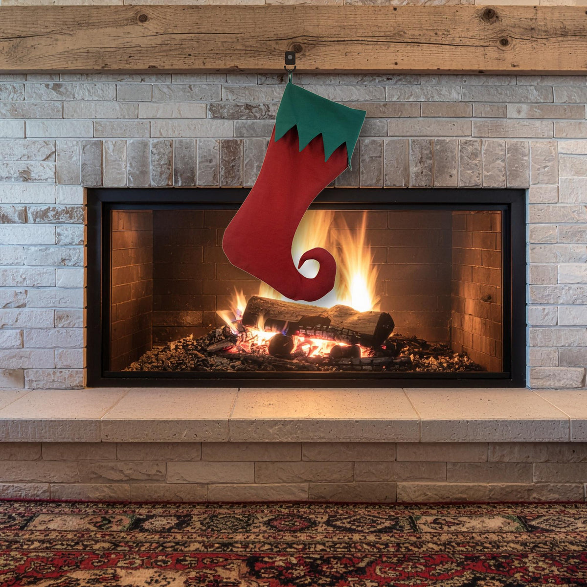 Red elf stocking with a green zigzag cuff and curled toe hanging on a fireplace mantel