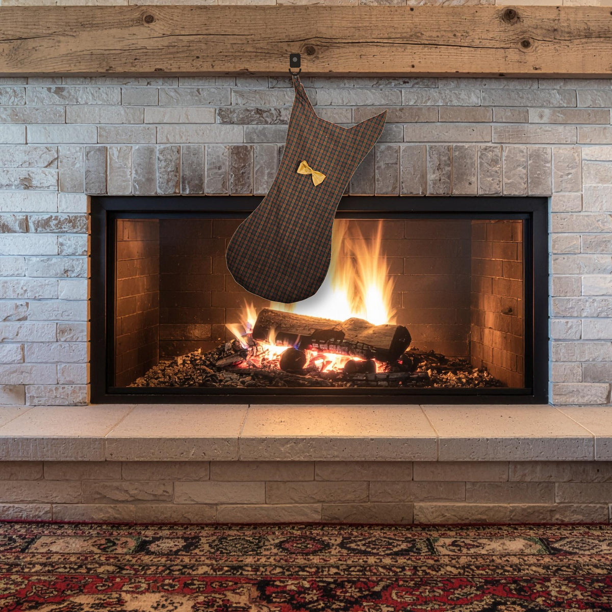 Brown plaid cat shaped stocking with a gold bow tie hanging over a lit fireplace